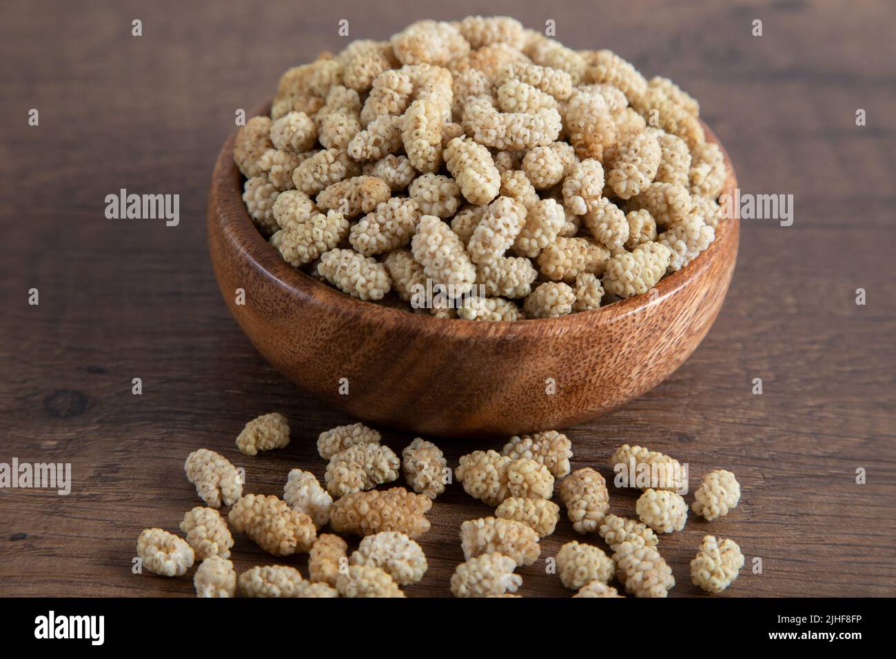 Ciotola piena di gelso secco su sfondo di legno Foto Stock