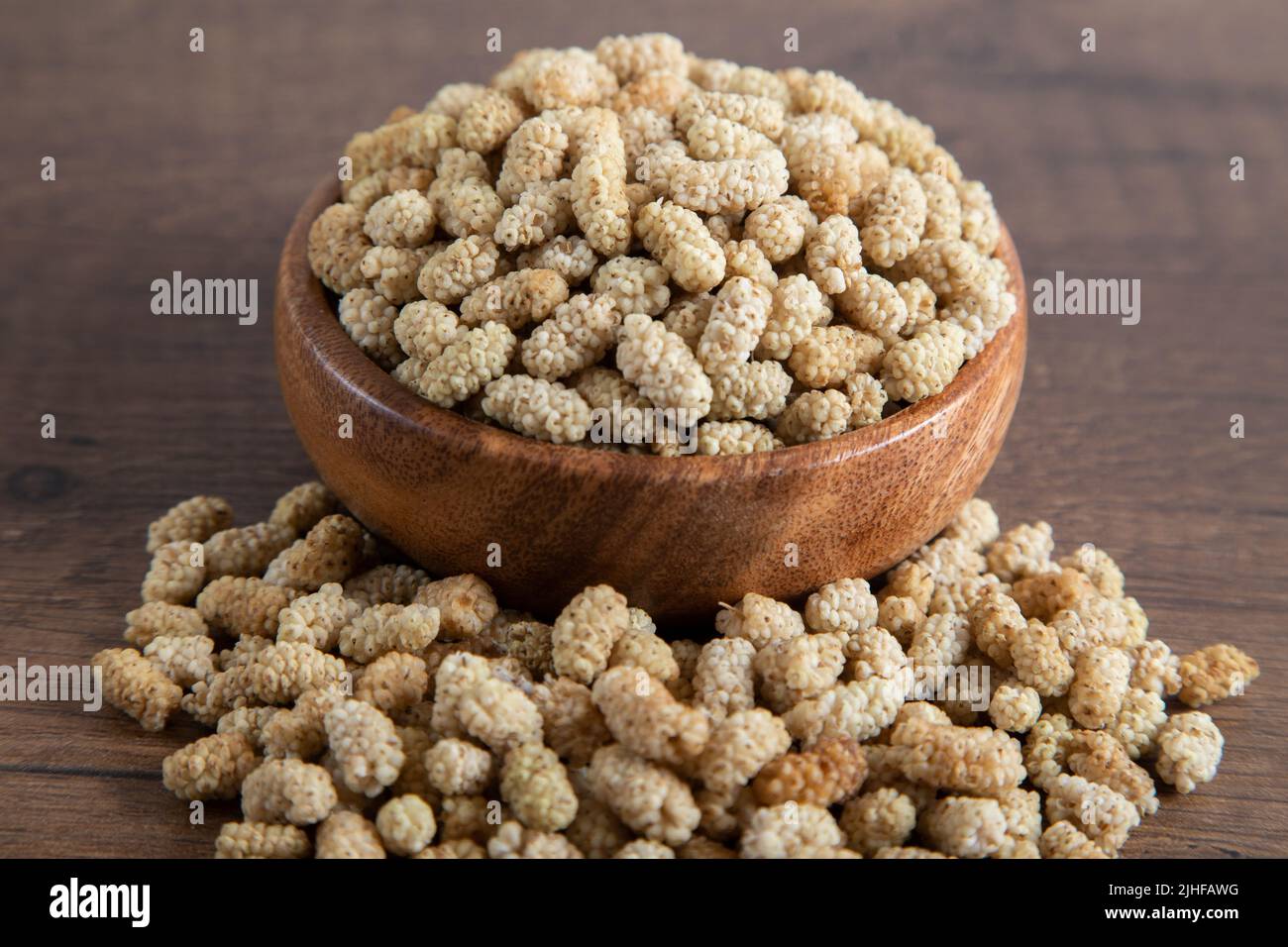 Ciotola piena di gelso secco su sfondo di legno Foto Stock