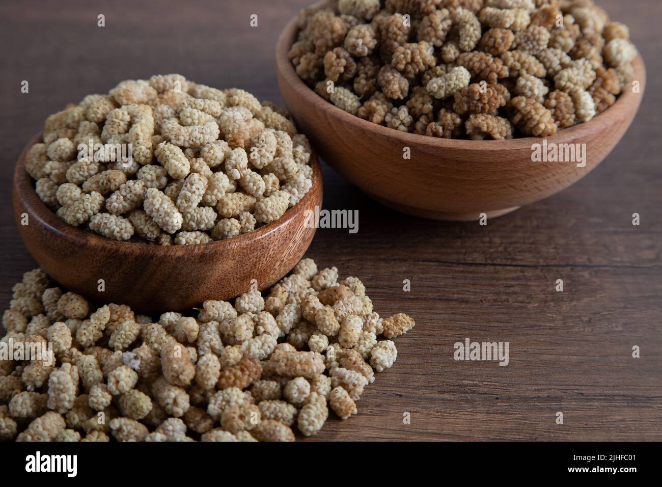 Ciotola piena di gelso secco su sfondo di legno Foto Stock