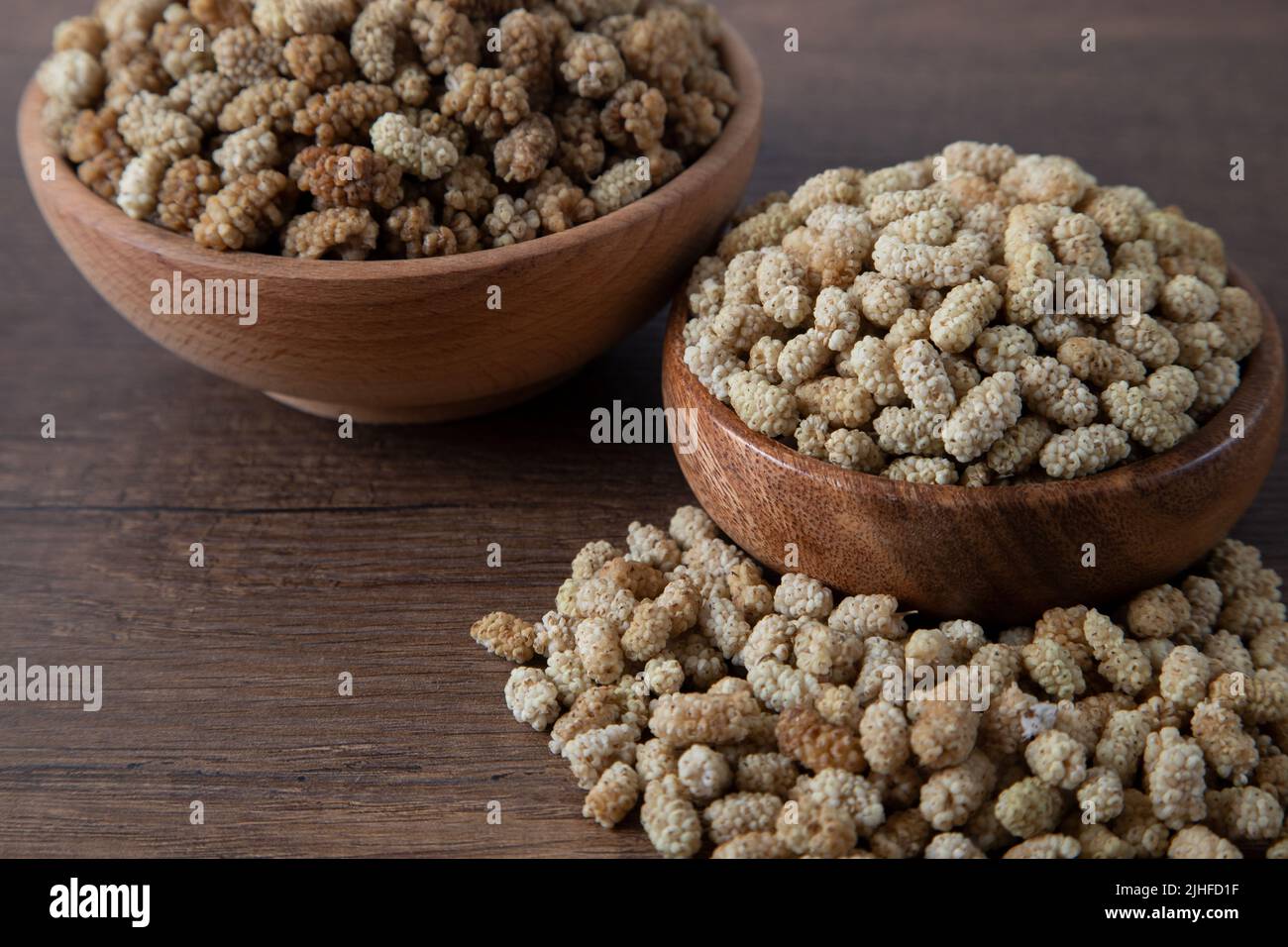 Ciotola piena di gelso secco su sfondo di legno Foto Stock