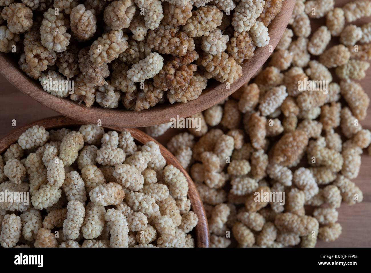 Ciotola piena di gelso secco su sfondo di legno Foto Stock
