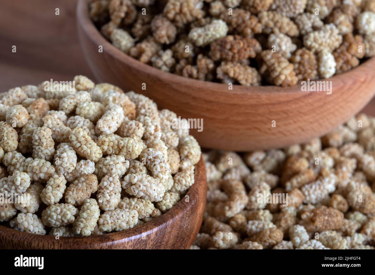 Ciotola piena di gelso secco su sfondo di legno Foto Stock