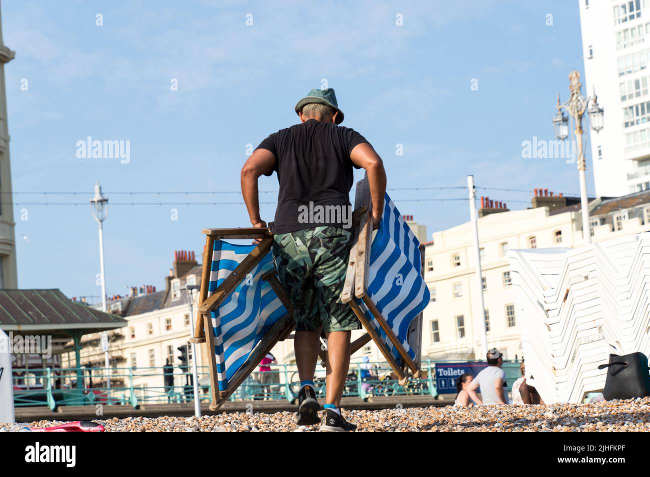 Persona che porta la sedia a sdraio di fronte alla spiaggia Foto Stock