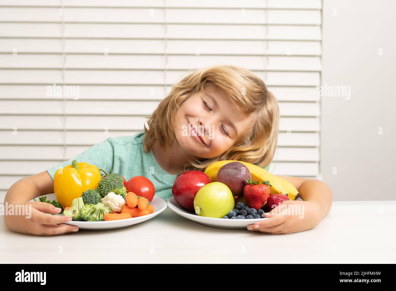 Frutta e verdura. Schoolkid che mangia la colazione prima della scuola. Ritratto del bambino sedersi alla scrivania in cucina di casa hanno gustoso nutriente delizioso Foto Stock