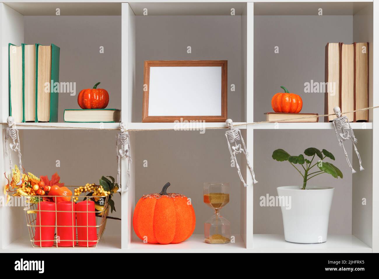 Halloween arredamento interno casa. Ripiani bianchi, cornici fotografiche, libri, pentole per piante, zucche. Foto Stock