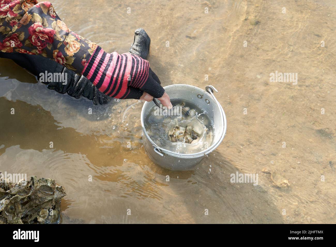 Ko Phangan, Thailandia, 15 marzo 2022: Donna che getta una vongola in un vaso sul mare Foto Stock