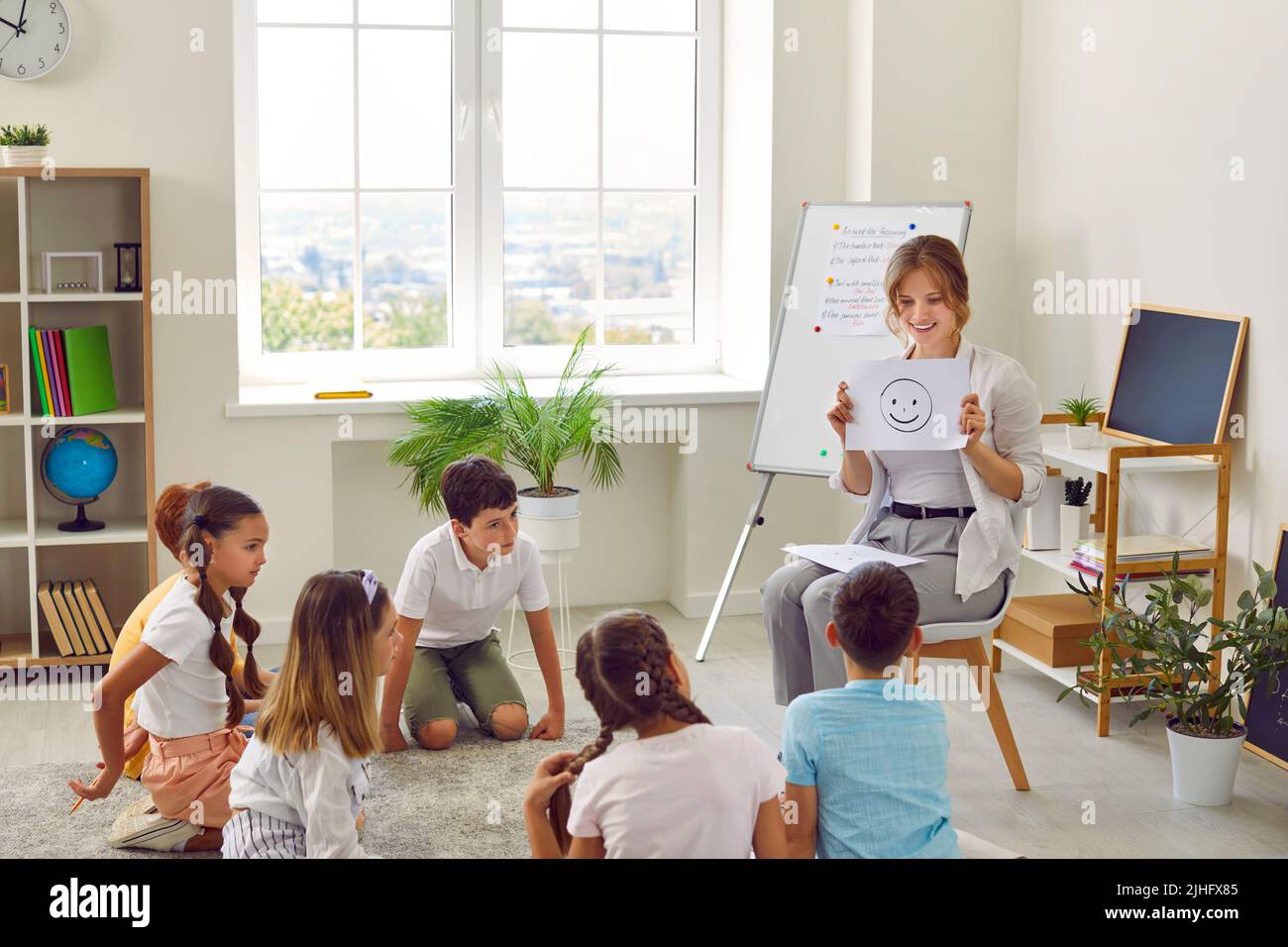 Lo psicologo della scuola parla delle emozioni durante l'incontro con un gruppo di studenti delle scuole elementari. Foto Stock