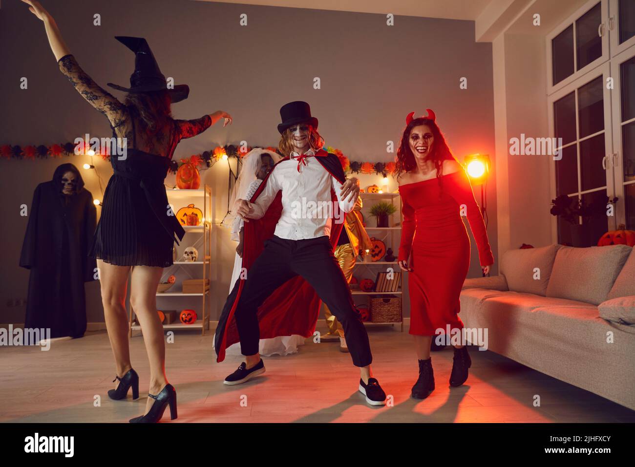 I giovani amici felici ballano e si divertono insieme alla festa di Halloween sera Foto Stock