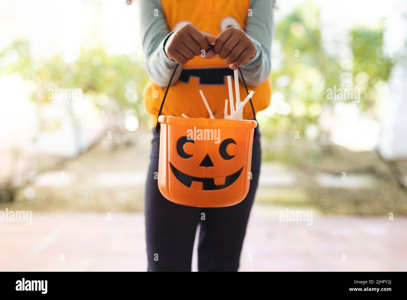 Immagine della sezione media della ragazza afroamericana in costume di Halloween con cestino Foto Stock