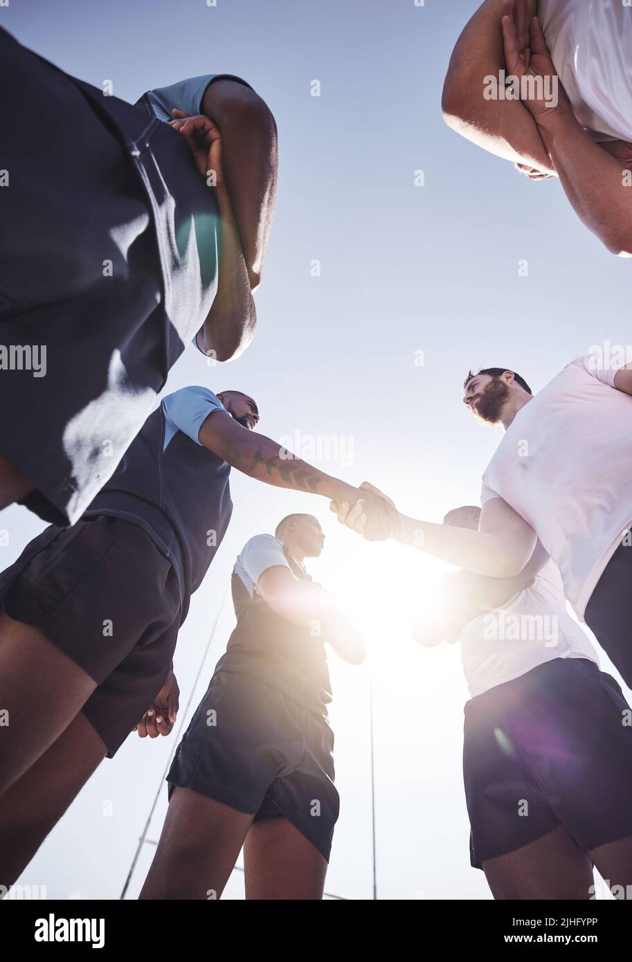 Al di sotto di due squadre di rugby avversari che scuotono le mani prima o dopo una partita fuori su un campo. I giocatori di Rugby condividono una stretta di mano per mostrare rispetto e. Foto Stock