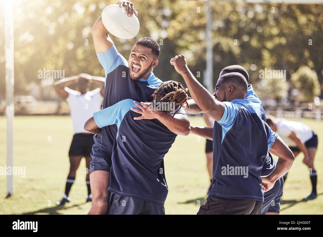 Diversi compagni di squadra di rugby che festeggiano la vittoria o la vittoria di una partita all'aperto in un campo sportivo. I giocatori di Rugby si acclamano durante una partita dopo aver fatto un Foto Stock