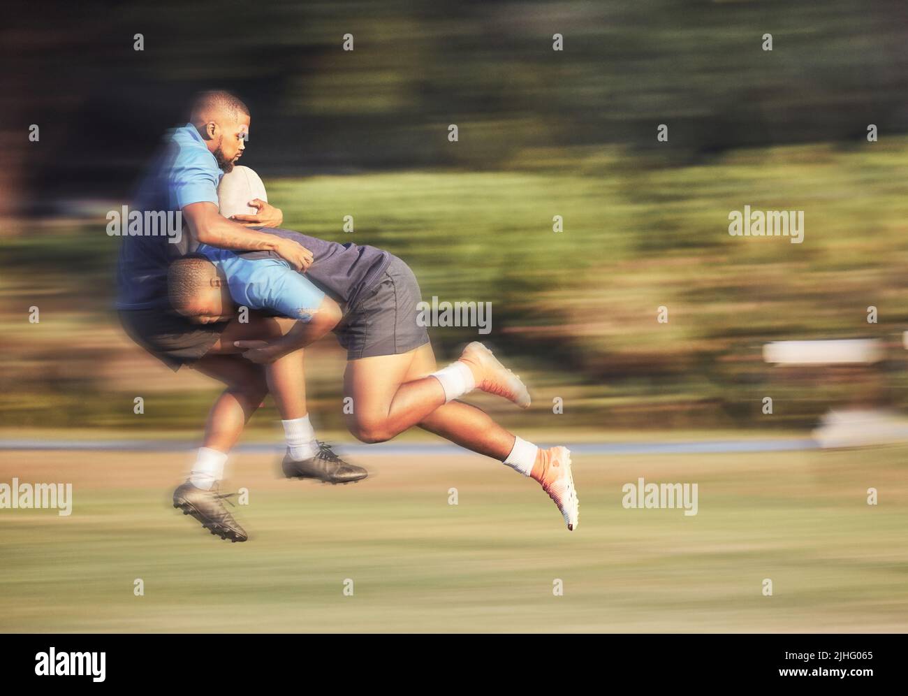 Giocatore di rugby misto che tenta di affrontare un avversario durante una partita di rugby fuori sul campo. Giovane ispanico che affronta un avversario in un Foto Stock