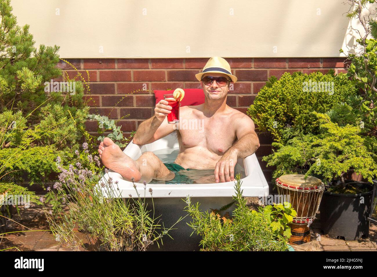 Kidderminster, Regno Unito. 18th luglio 2022. Tempo del Regno Unito: Con temperature elevate c'è solo un modo per raffreddarsi - Lee Hudson decide di prendere la giornata e saltare nella sua piscina a tuffo fatta in casa! Il caldo di oggi scorching dà l'occasione perfetta riutilizzare una vecchia vasca da bagno come piscina di tuffo per il giorno prima di riciclare la vecchia vasca. L'acqua fredda in vasca ha raggiunto i 28 gradi a metà pomeriggio rendendola ideale per un bagno rilassante e una bevanda fruttata per reidratare. Credit: Lee Hudson/Alamy Live News Foto Stock