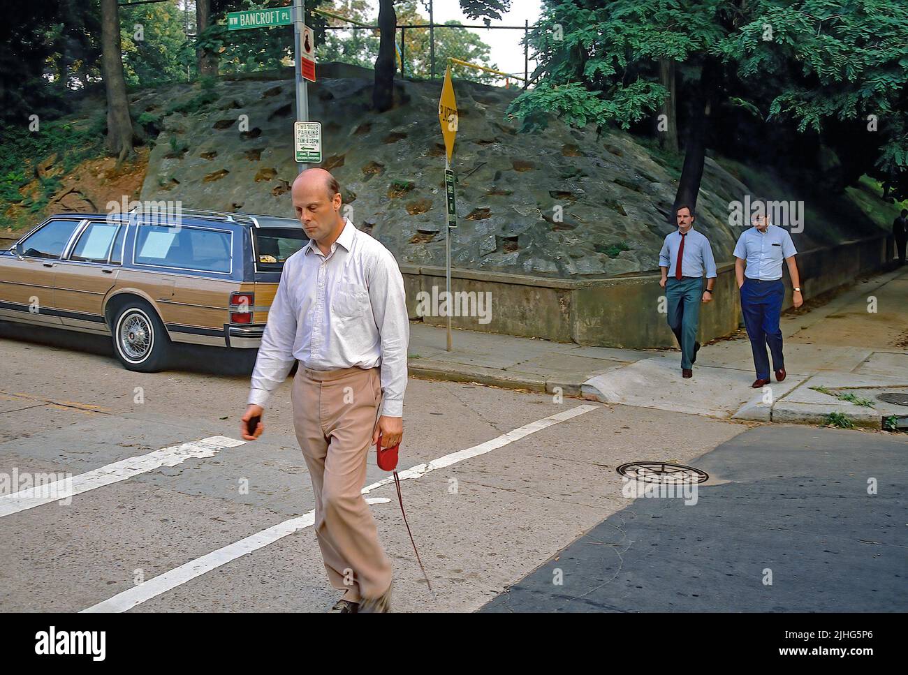 WASHINGTON DC - AGOSTO 1989Felix Bloch (pantaloni tan con camicia bianca) ex direttore degli affari europei e canadesi per il Dipartimento di Stato degli Stati Uniti, collegato al caso spia Robert Hanssen (agente FBI), Cammina il suo cane lungo Bancroft St NW nella sezione Embassy Row di Washington.He è seguito da due agenti maschi FBI, ma non è mai stato accusato di alcun crimine. Credito: Mark Reinstein/MediaPunch Foto Stock