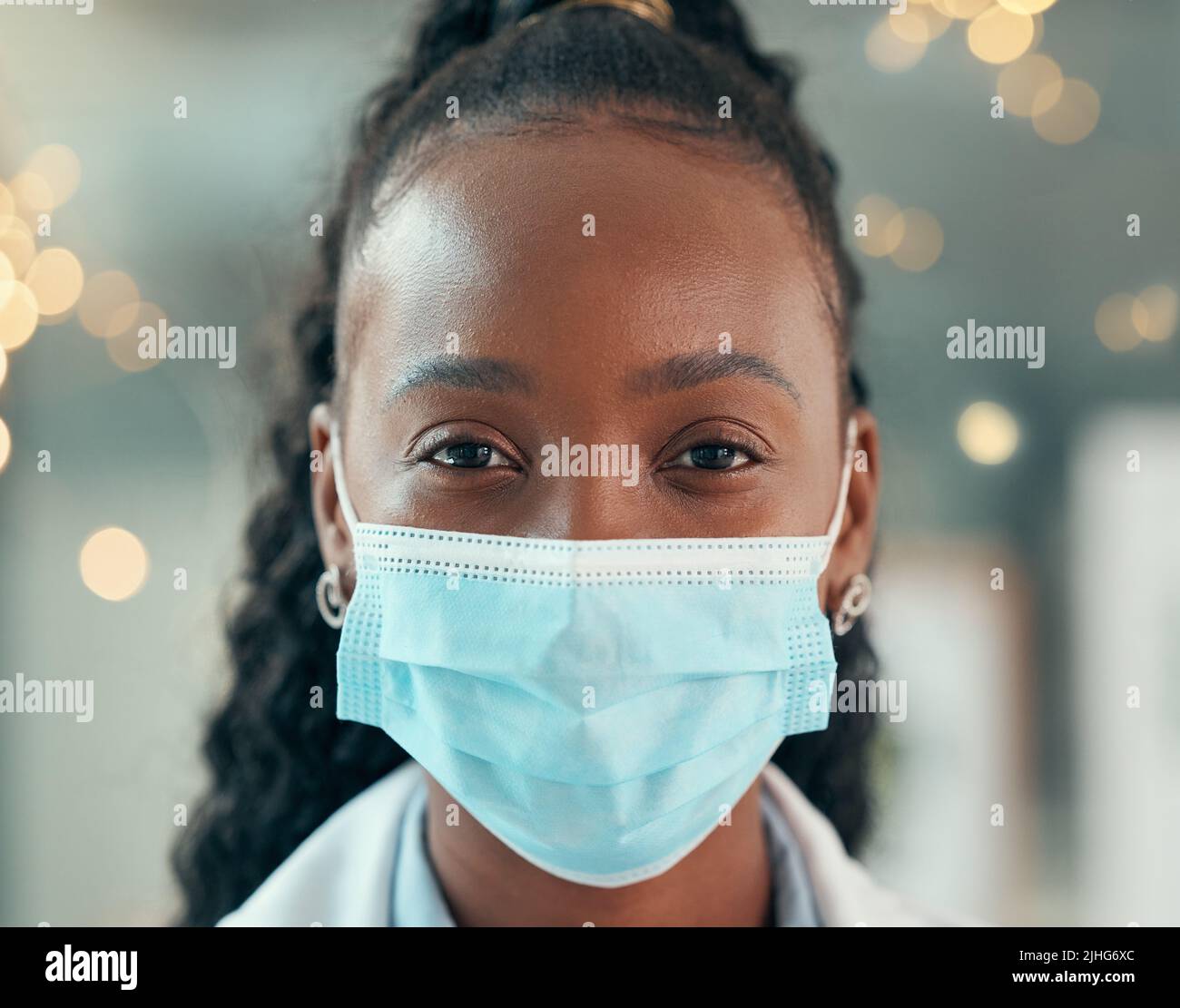 Faccia anteriore del medico che indossa una maschera covid. Medico afroamericano primo piano in ufficio. Ritratto di medico afroamericano nella sua clinica. Verticale Foto Stock