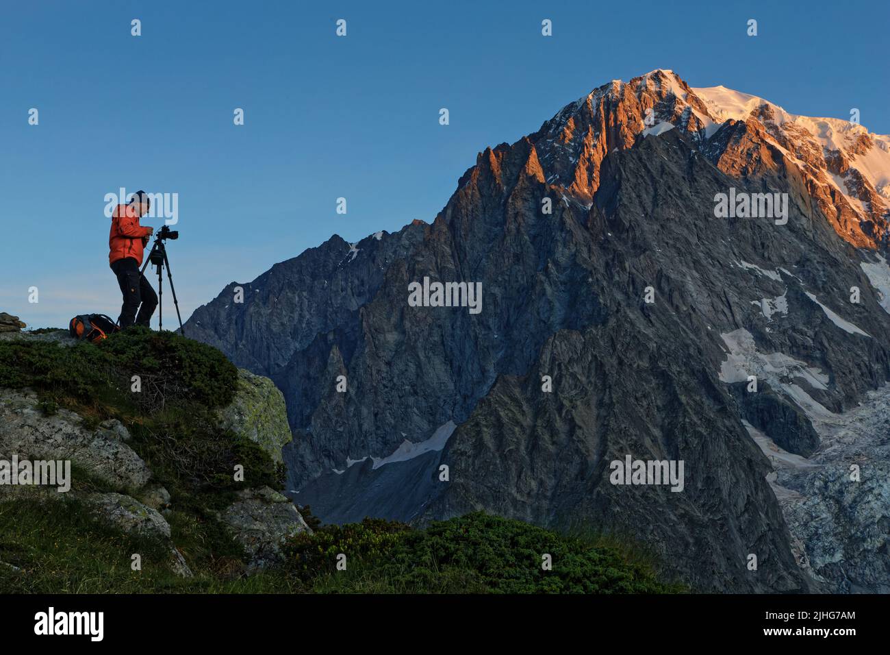 COURTMAYEUR, ITALIA, 10 luglio 2022 : un fotografo lavora all'alba sotto le cime del Monte Bianco. Foto Stock