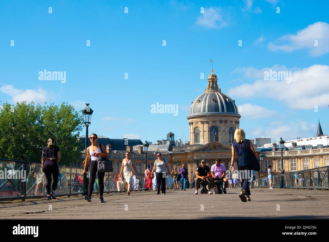 Persone che camminano attraverso Pont des Arts o Passerelle des Arts un ponte pedonale a Parigi preso da basso livello con la cupola dell'Institut de France Foto Stock