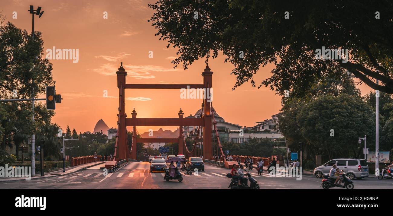 Guilin, Cina - Agosto 2019 : traffico di auto e scooter in tarda serata sul ponte Rosso sul fiume li in via Sanduo Lu al tramonto, provincia di Guangxi Foto Stock