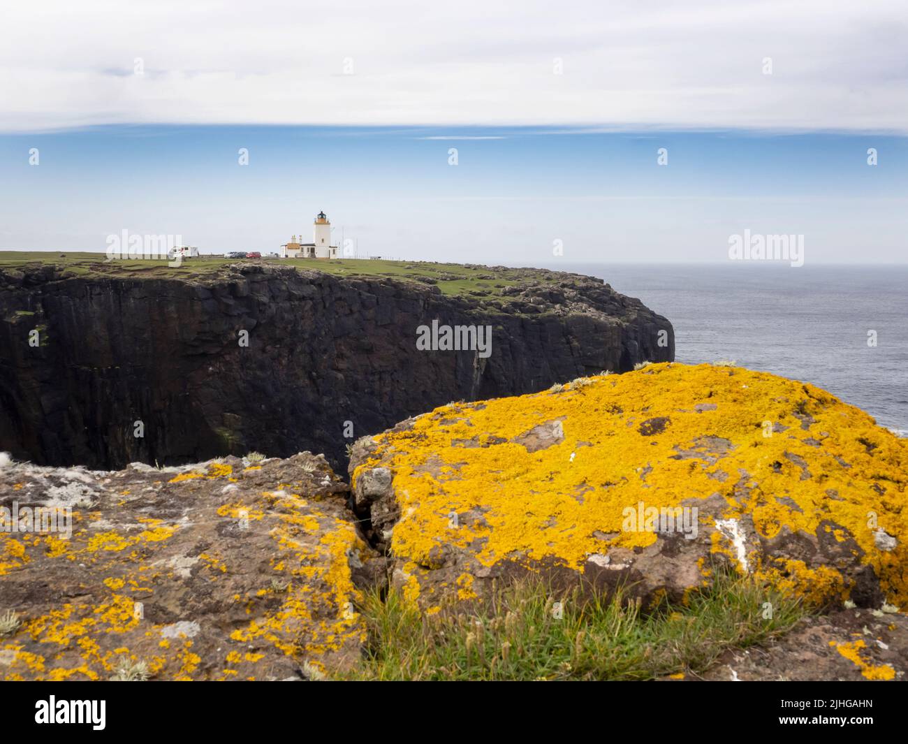 Calder's Geo su Esha Ness, Mainland Shetland, Scozia, Regno Unito con il faro di Esha Ness sullo sfondo. Foto Stock