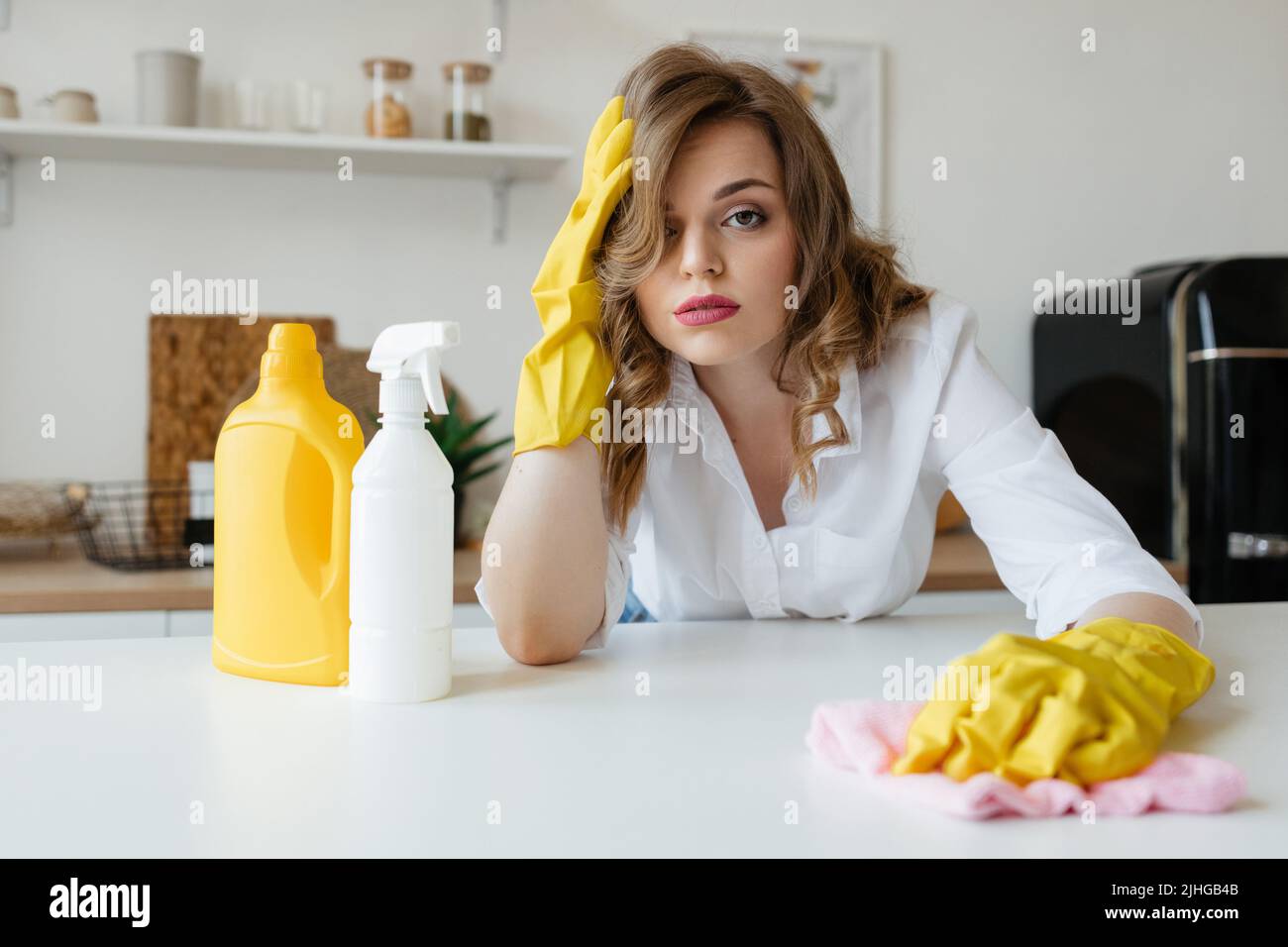 Bella ragazza casalinga sta cercando di asciugare le macchie dal tavolo da cucina Foto Stock