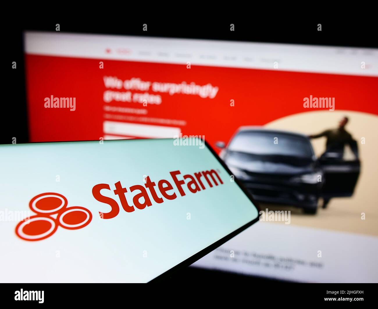 Smartphone con logo della state Farm Mutual Automobile Insurance Company sullo schermo di fronte al sito Web aziendale. Concentrarsi sul centro del display del telefono. Foto Stock