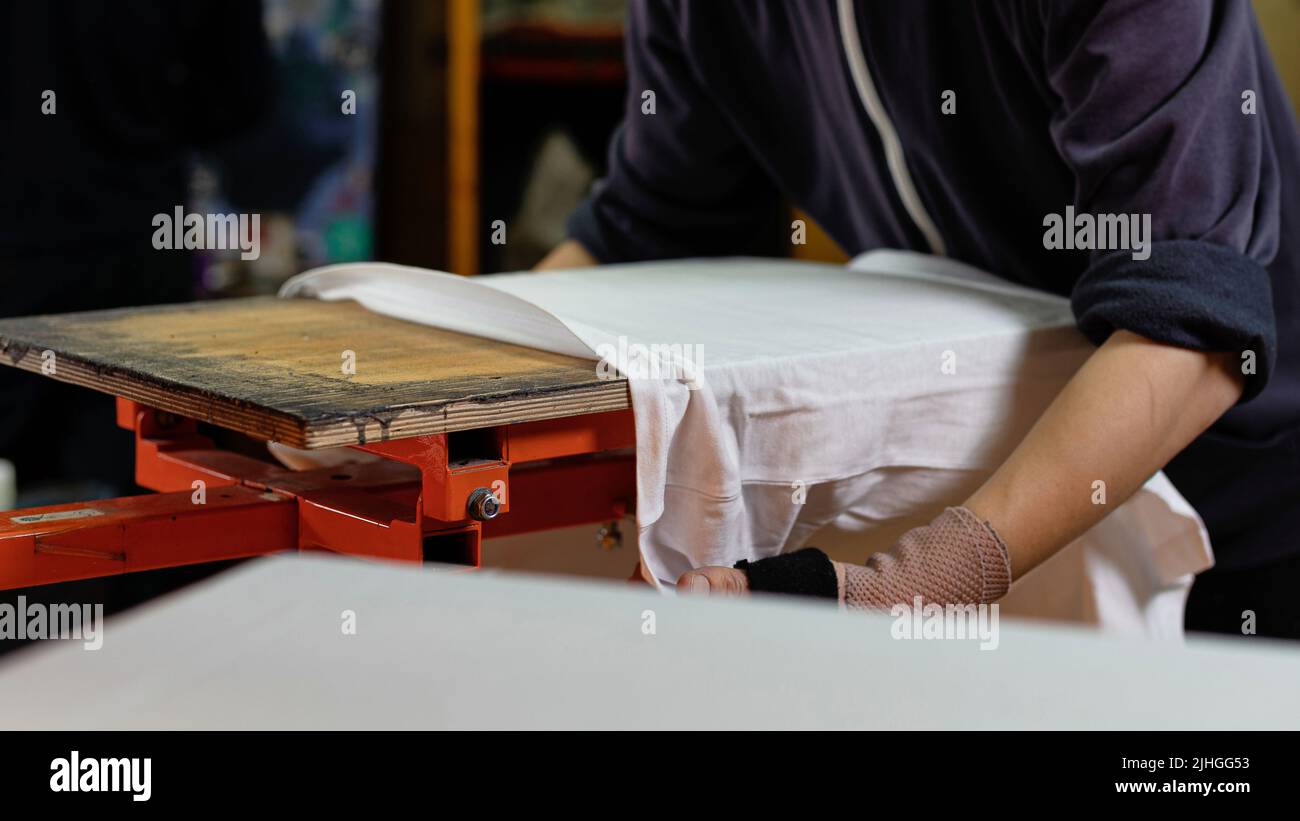 t-shirt bianca in un uomo pronto per la stampa. stampa su t-shirt in officina. serigrafia produzione. serigrafia stampa fuoco selettivo ph Foto Stock