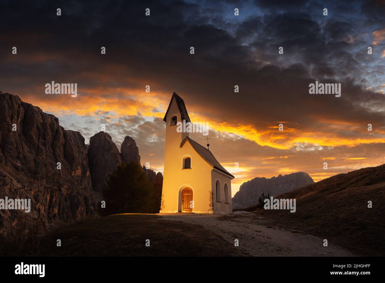 Incredibile vista sulla piccola cappella iIlluminated - Kadelle Ciapela sul Passo Gardena, Dolomiti Italiane. Tramonto colorato nelle Alpi dolomitiche, Italia. Fotografia di paesaggio Foto Stock