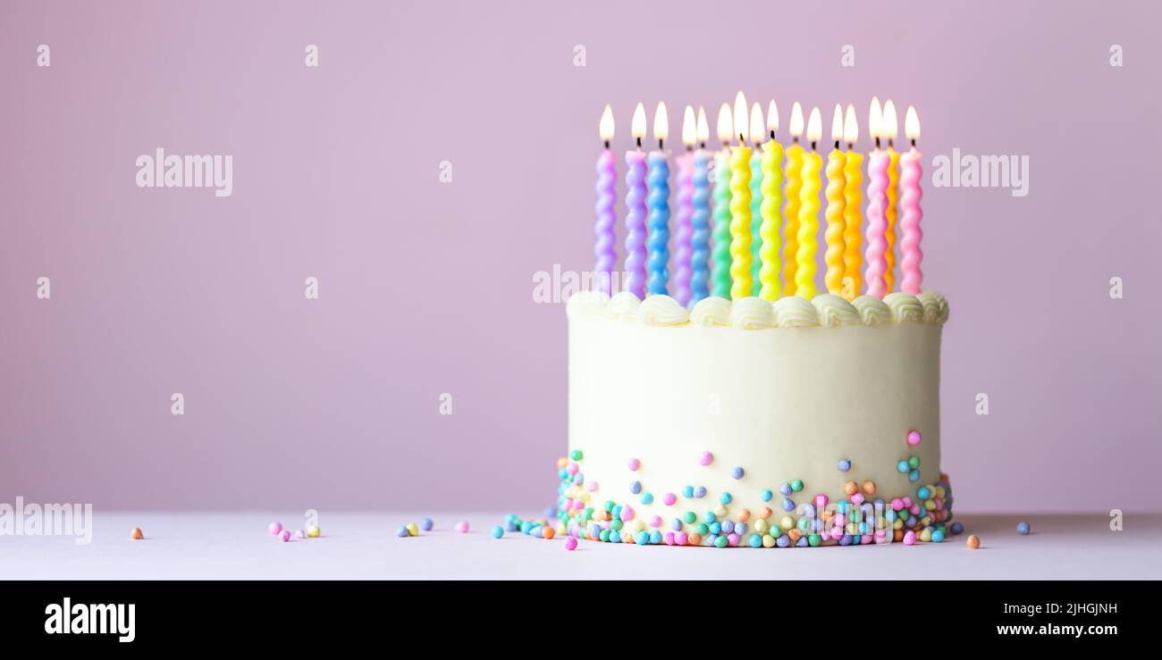 Sfondo torta di compleanno arcobaleno con colorate candele arcobaleno Foto Stock