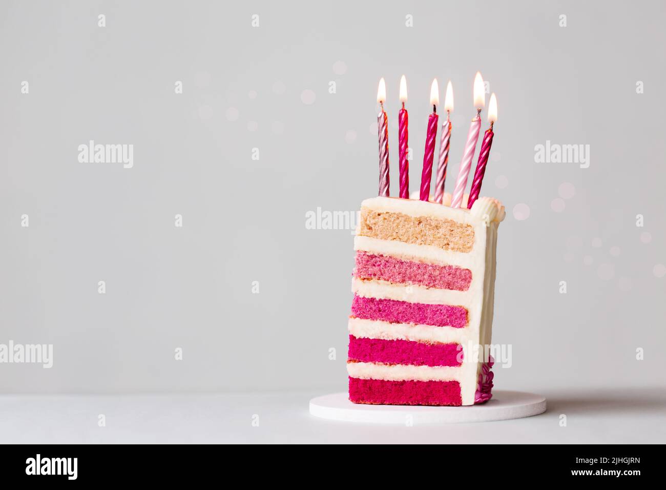 Fetta di torta rosa di compleanno ombre con sei candele rosa di compleanno per festeggiare un compleanno Foto Stock