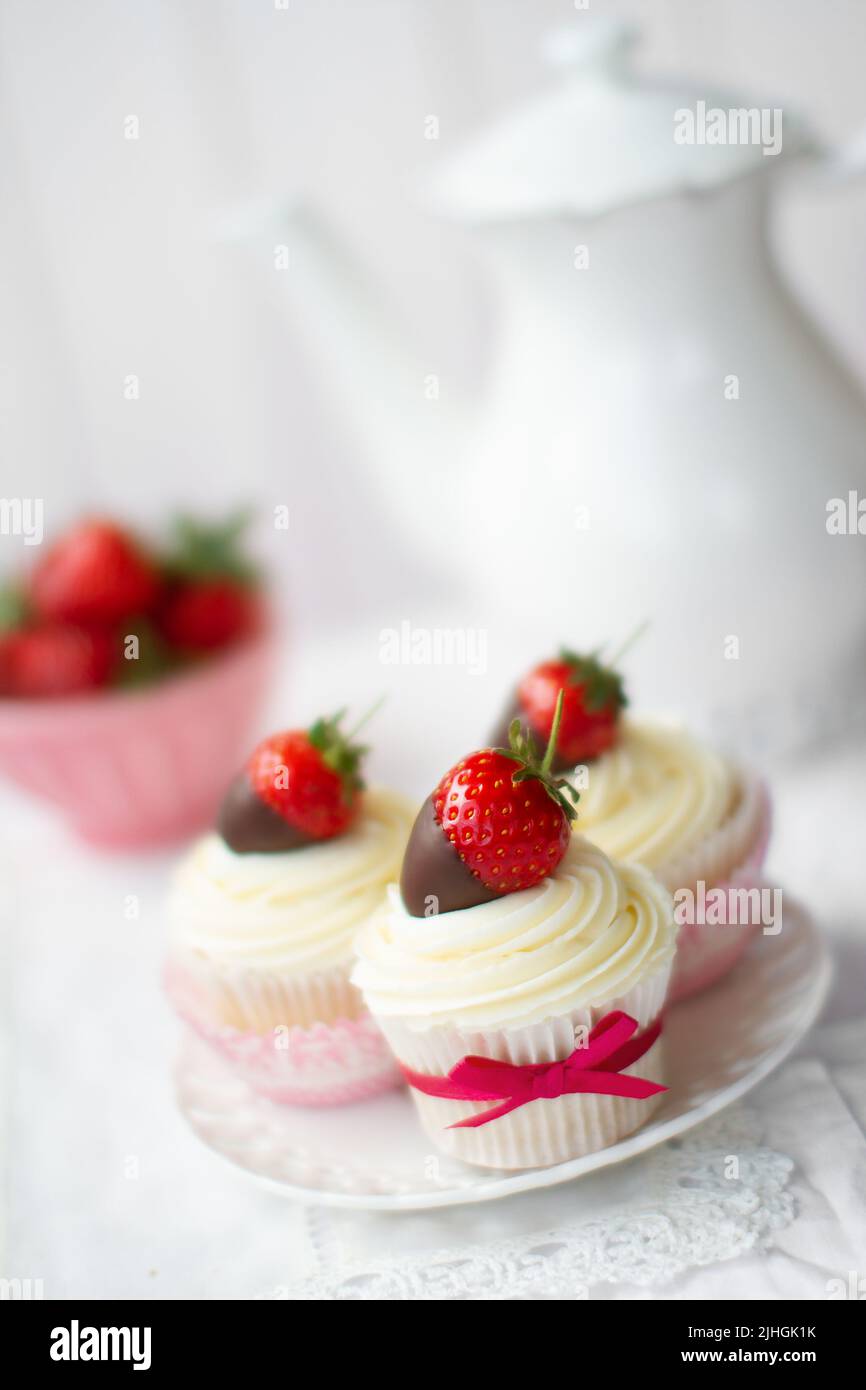 Tè pomeridiano servito con fragole e cupcake decorati con panna Foto Stock