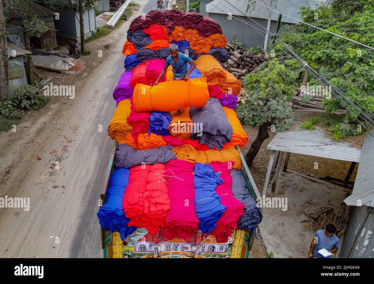 Le coperte colorate vengono caricate sui camion dai lavoratori. Industria tessile in Bangladesh Foto Stock