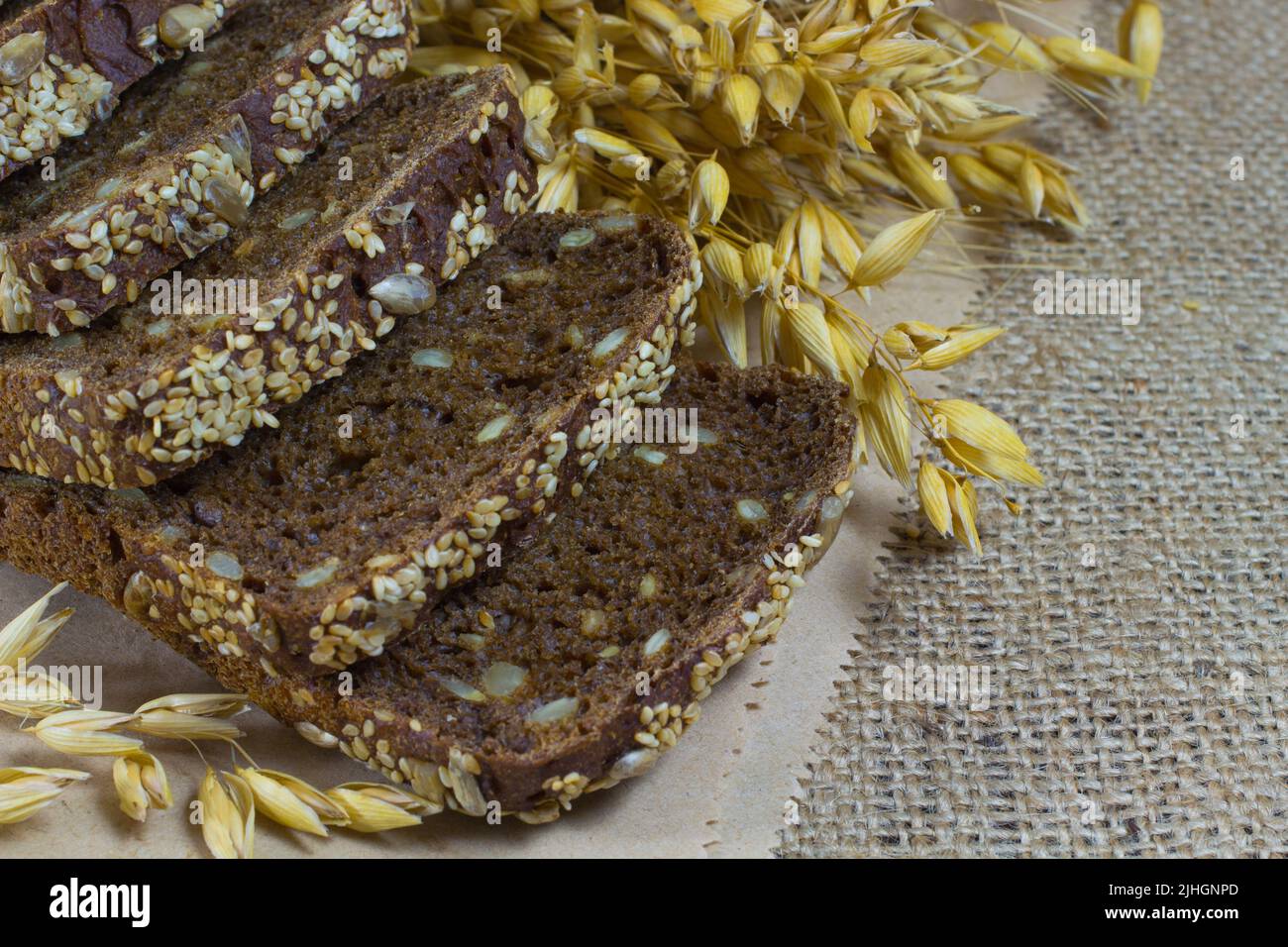 Pane nero con semi di sesamo e semi di girasole, spighe di grano su imballaggio Foto Stock