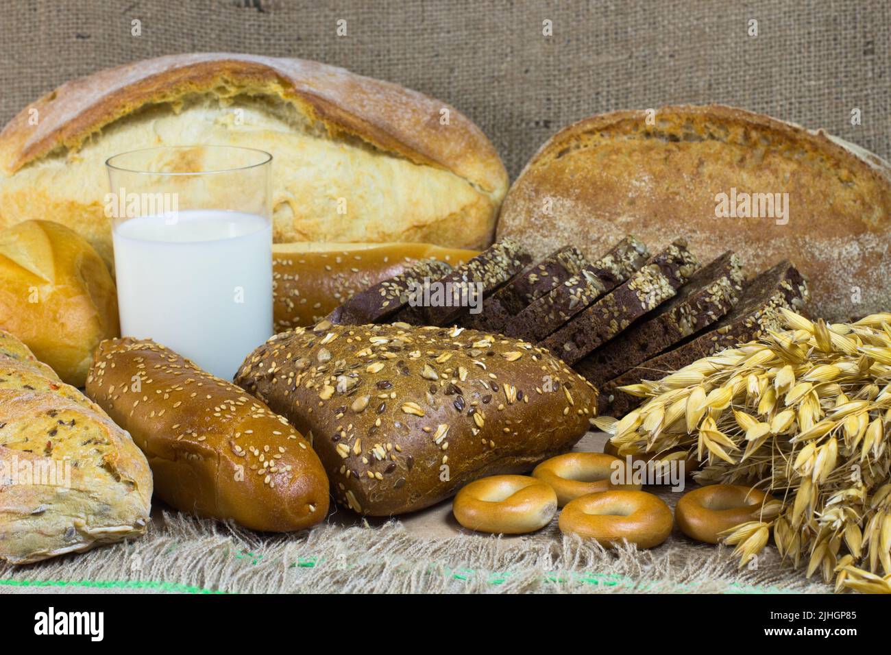 Pane bianco e nero, baguette, panna, un mazzo di avena, un bicchiere di latte sul sacco Foto Stock