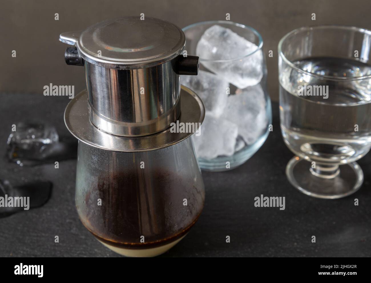 Un tradizionale modo vietnamita di preparare il caffè utilizzando un filtro speciale - phin. Caffè con latte condensato e ghiaccio. Foto Stock