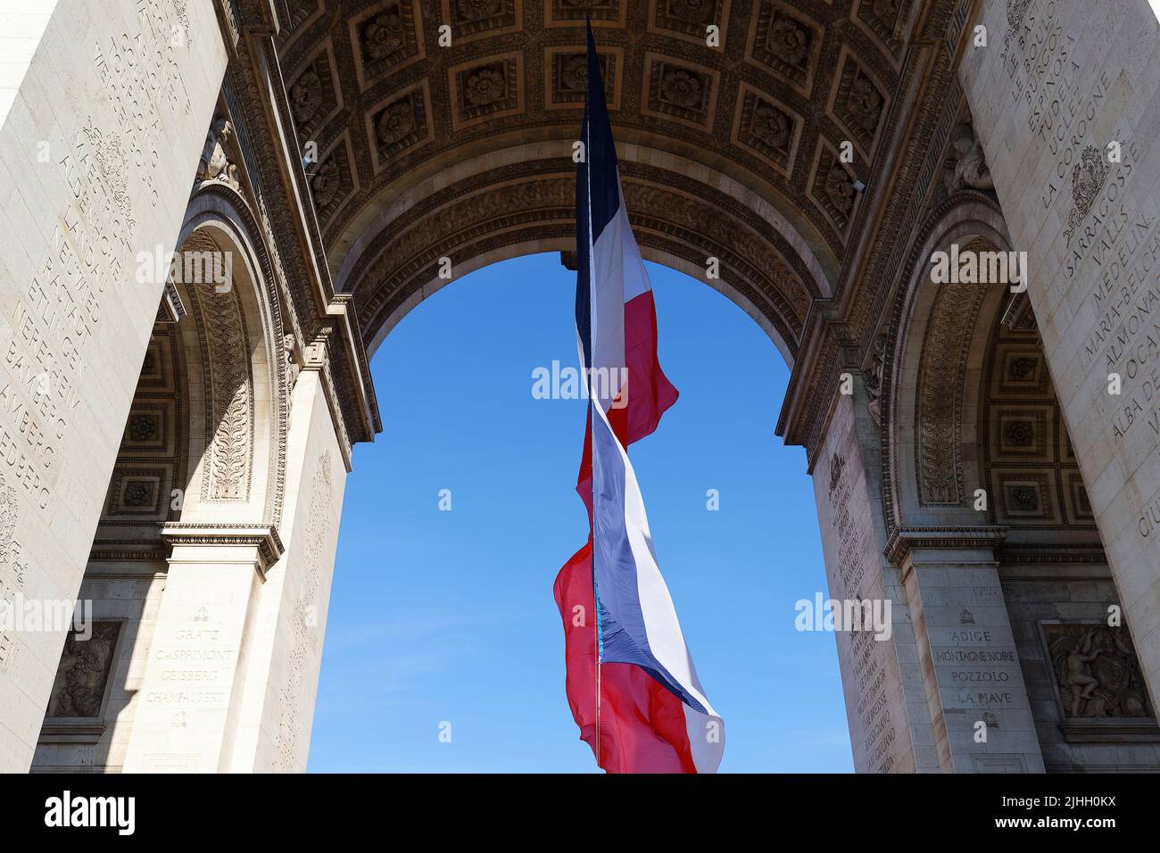 La bandiera francese sotto l'arco Triumfale. La tomba del soldato sconosciuto. Parigi, Francia. Iscrizione su arco in francese: Nomi delle battaglie - nome proprio Foto Stock
