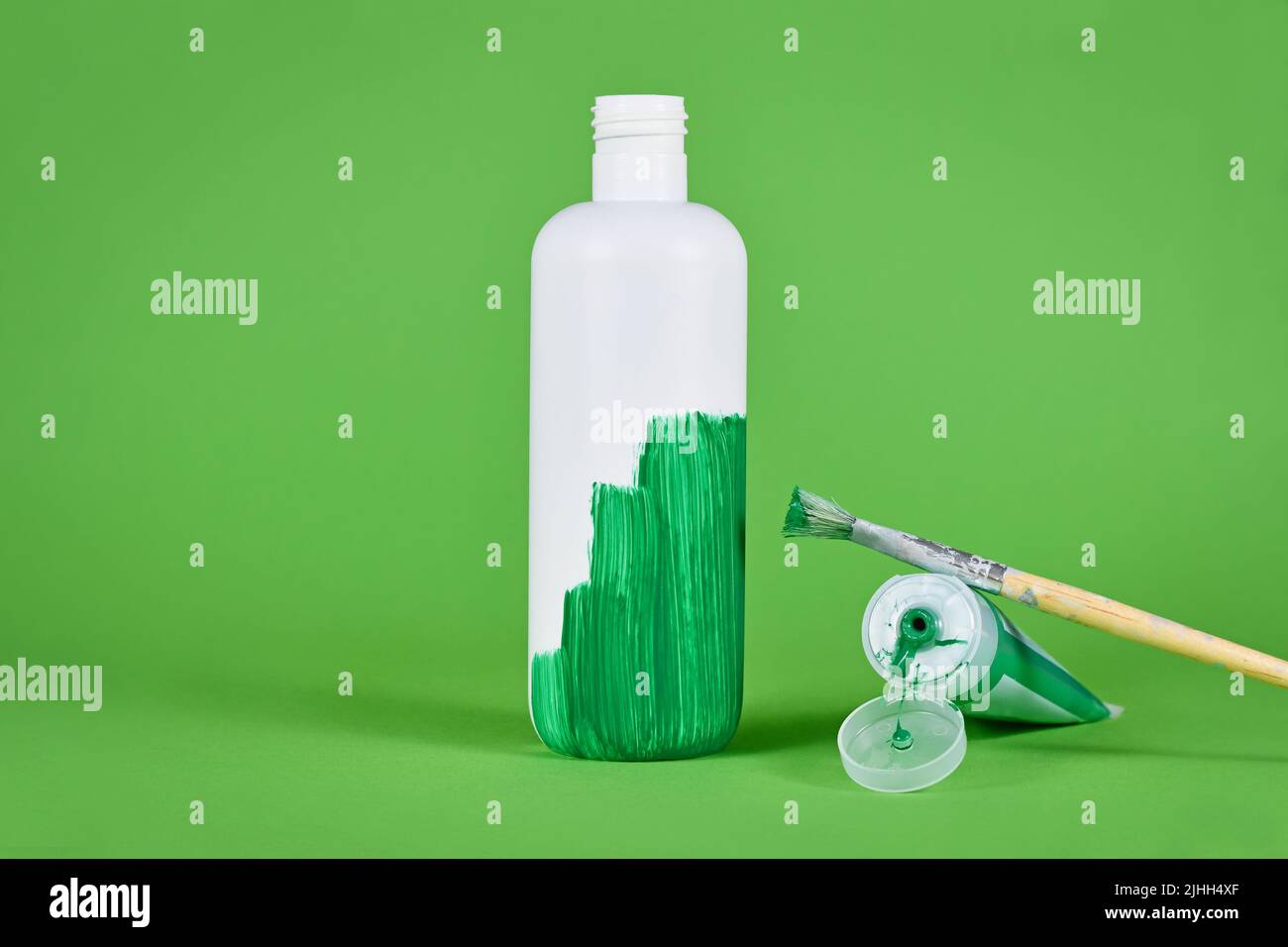 Concetto di lavaggio del verde con bottiglia di plastica bianca verniciata di verde Foto Stock