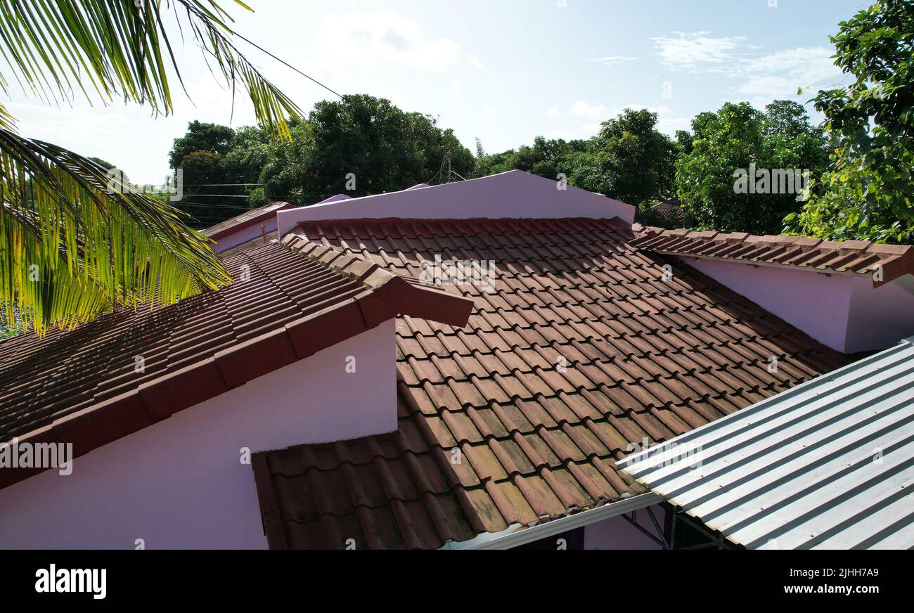 Tegole di argilla rossa e tetto in metallo in casa residenziale su sfondo cielo blu Foto Stock