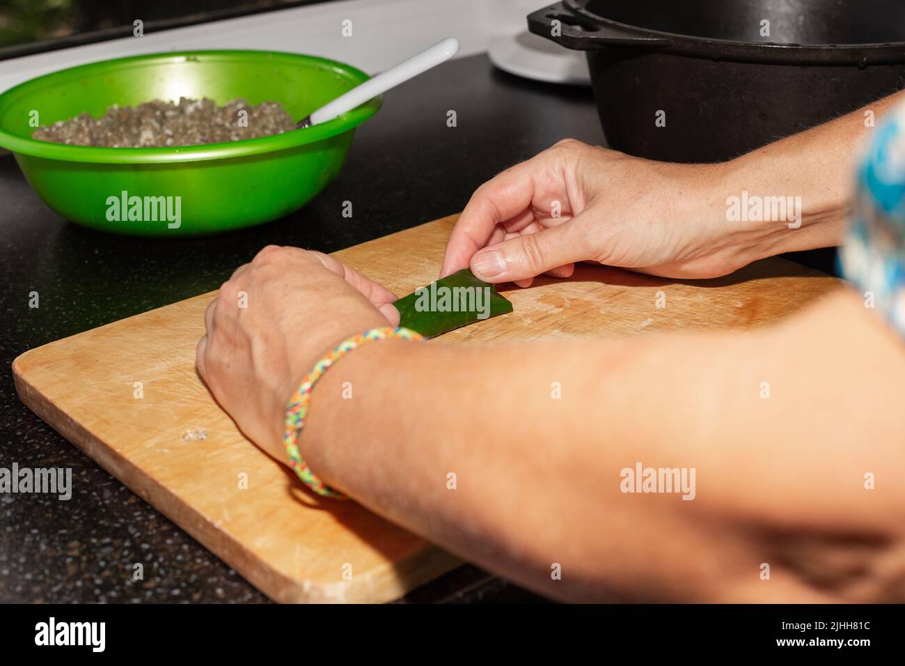 Una donna infila foglie d'uva con carne. Cucina caucasica piatto dolma. Foto Stock