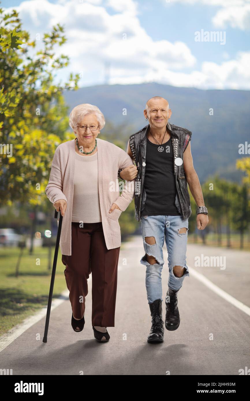 Uomo che aiuta una donna anziana con una canna da passeggio su un sentiero pedonale Foto Stock