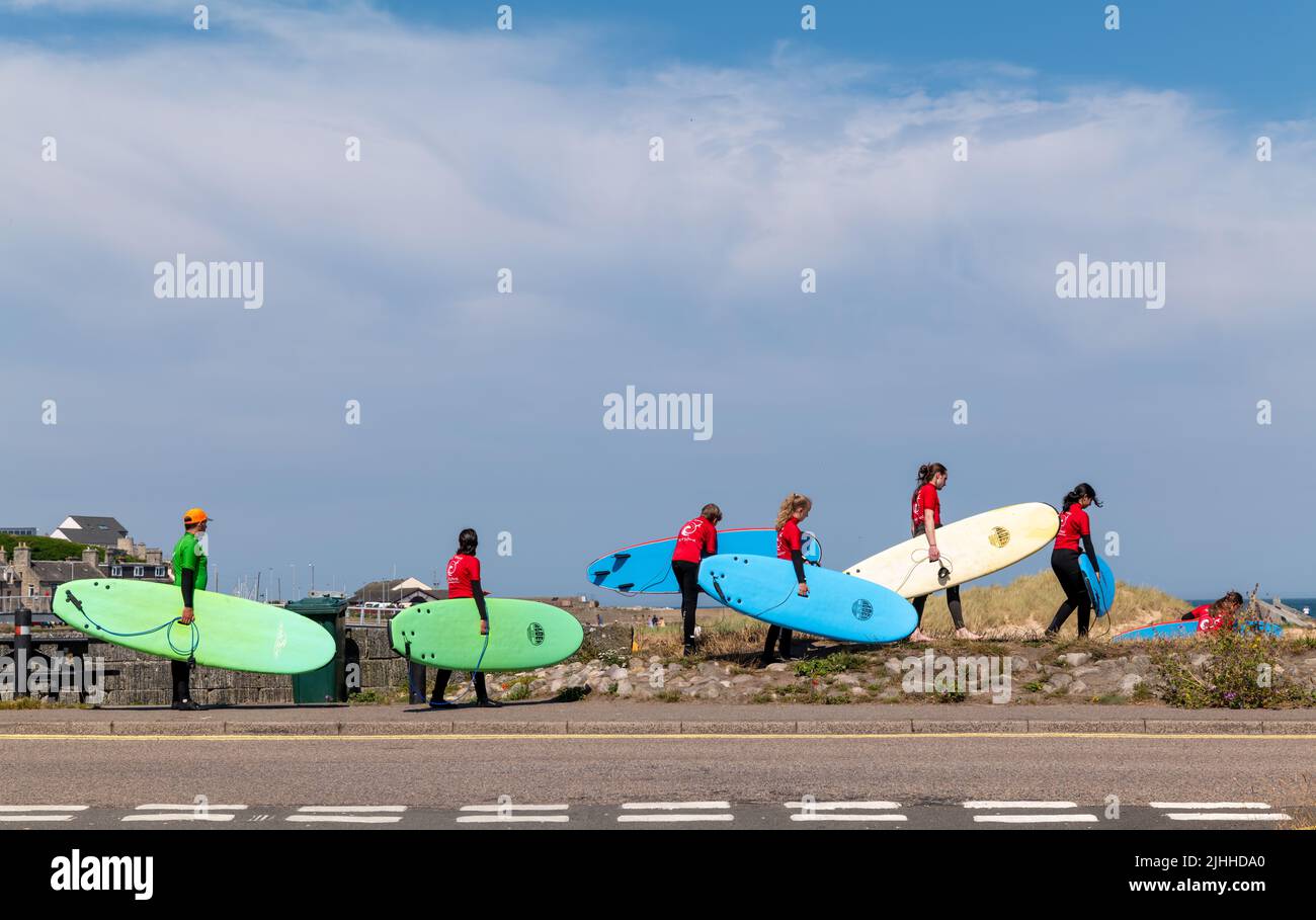18 luglio 2022. Lossiemouth, Moray, Scozia. Si tratta di un istruttore dietro un gruppo di studenti che vanno alla lezione di surf. Foto Stock