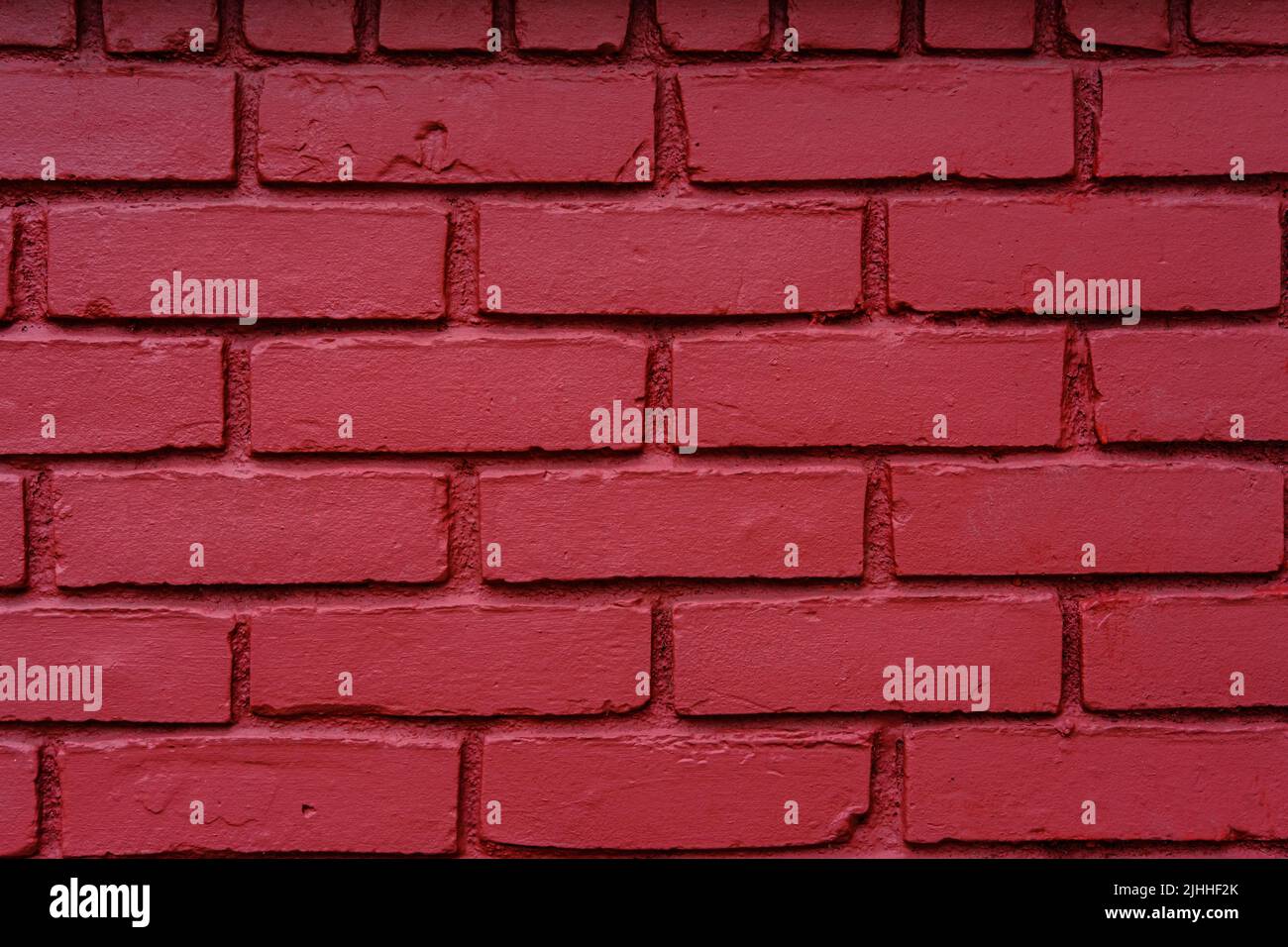 Fotografia di un vecchio muro di mattoni con un fresco cappotto di vernice rossa. Foto Stock