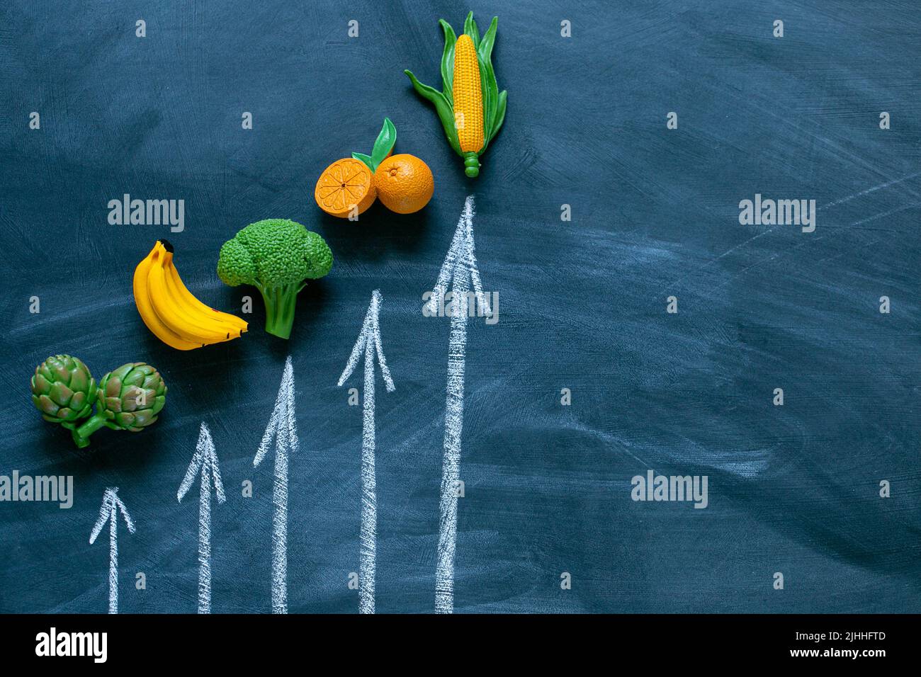 Cibo aumento prices.Vegetes.Vegetes e frutta aumento prezzo. Cibo crisi.Decorative verdure e frutta e frecce su bordo gesso sfondo. Cibo Foto Stock