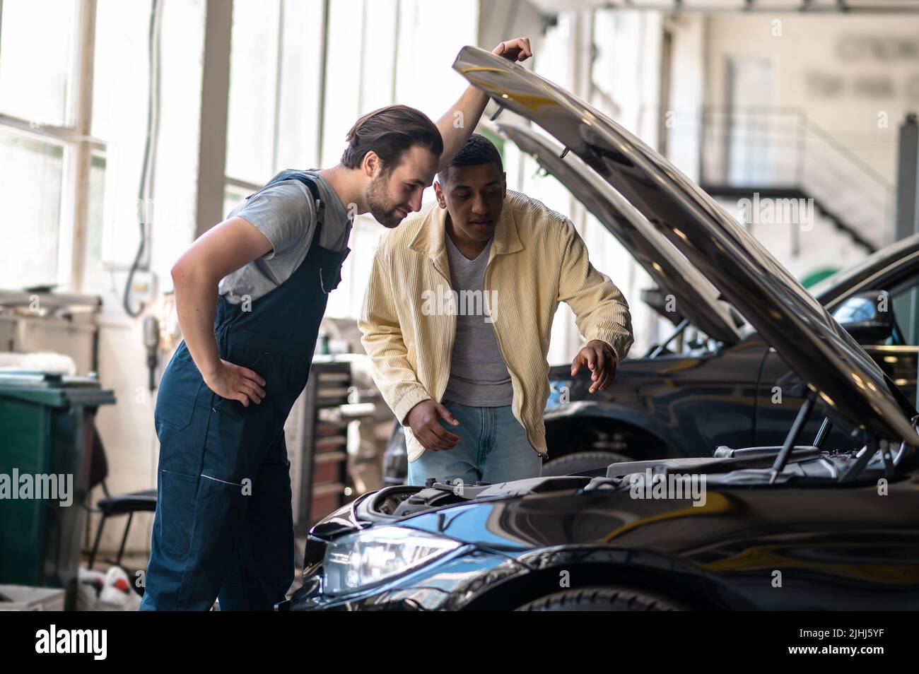 Due uomini che guardano nel cofano aperto dell'automobile Foto Stock