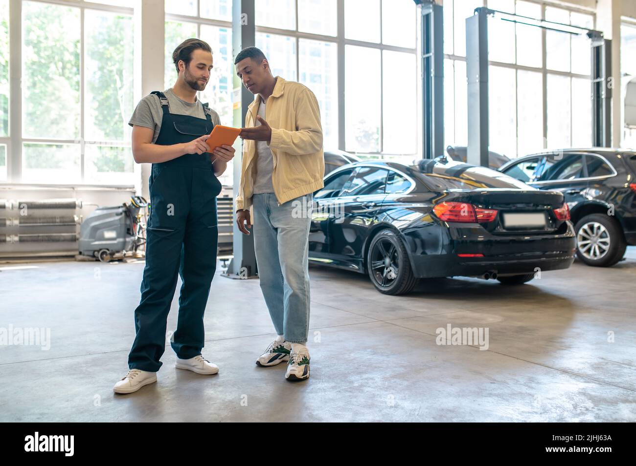 Due uomini che guardano il tablet in piedi in officina Foto Stock