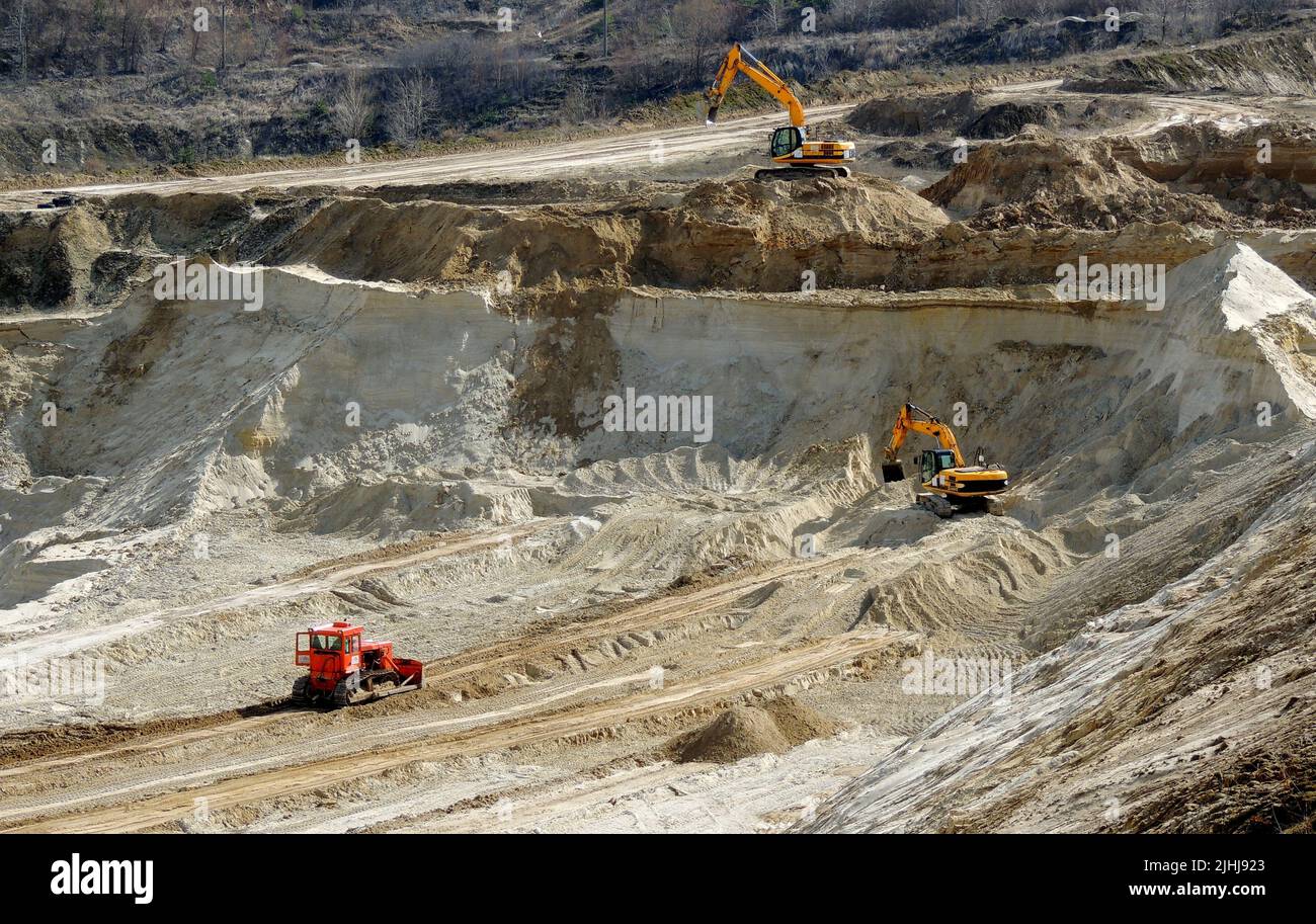 Escavatori pesanti e bulldozer lavorano in cave di sabbia industriali Foto Stock