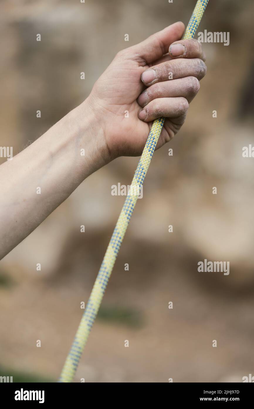 Colore primo piano di una mano umana che tiene una corda di arrampicata su roccia. Foto Stock