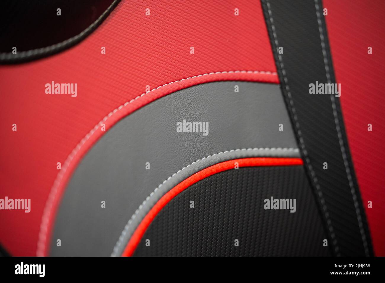 Moderna vettura sportiva con interni in pelle nera e rossa. Parte dei dettagli dei sedili in pelle con cuciture bianche. Foto Stock
