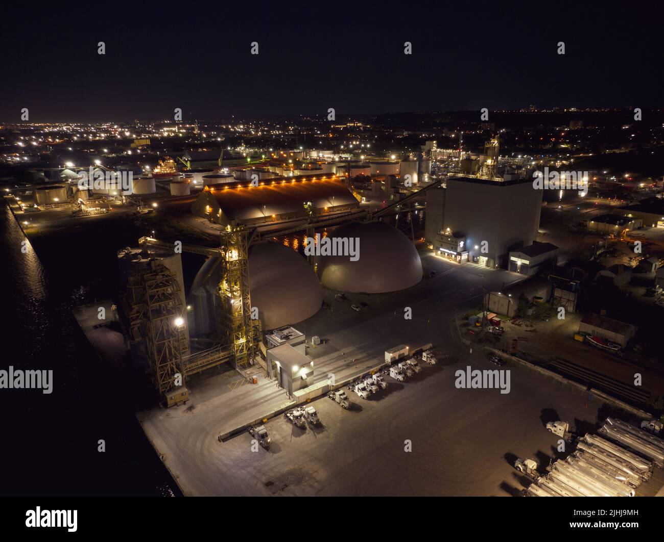 Una vista aerea che guarda un impianto agricolo industriale e le cupole di stoccaggio, raffigurate a tarda notte, con alcune luci accese. Foto Stock