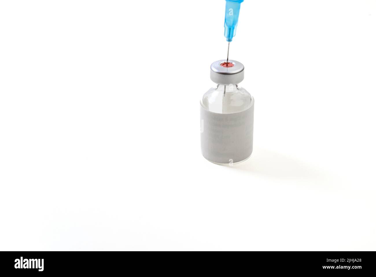 Flacone di vaccino con etichetta bianca e siringa su sfondo bianco Foto Stock