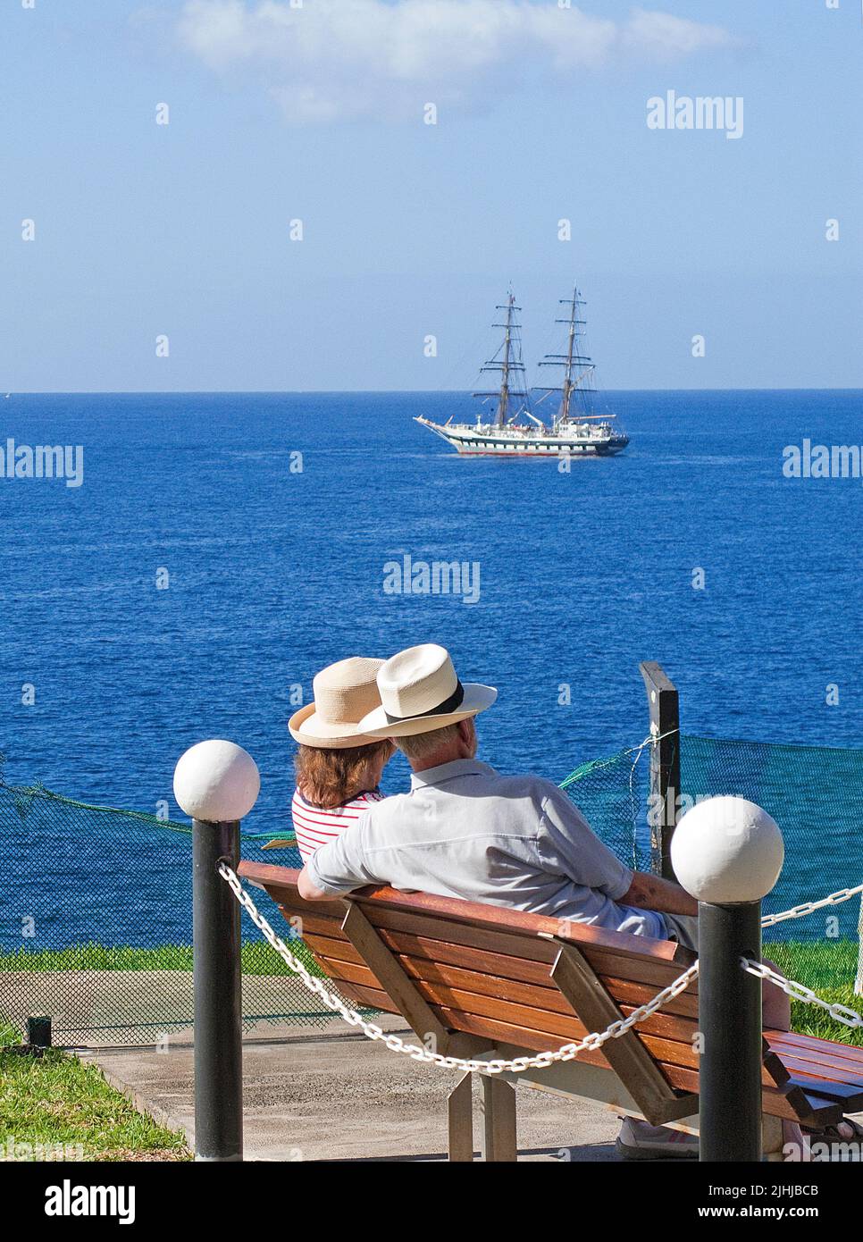 Coppia anziana con cappelli di paglia seduti su una panca e godendo di vista mare, Taurito, Grand Canary, Isole Canarie, Spagna, Europa Foto Stock